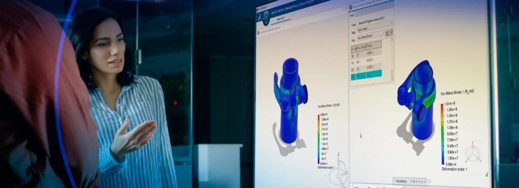 A woman in a professional setting discusses structural simulation results displayed on a large screen.
