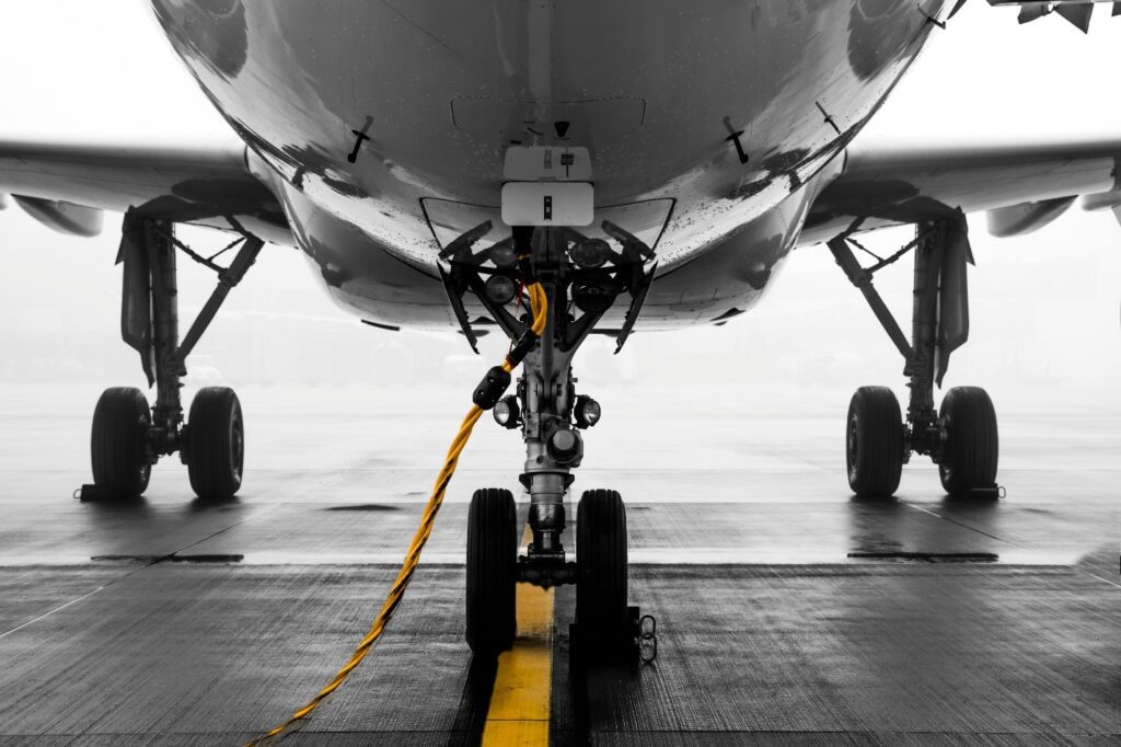 A close-up view of an aircraft's landing gear, captured from the front while parked on a wet tarmac.